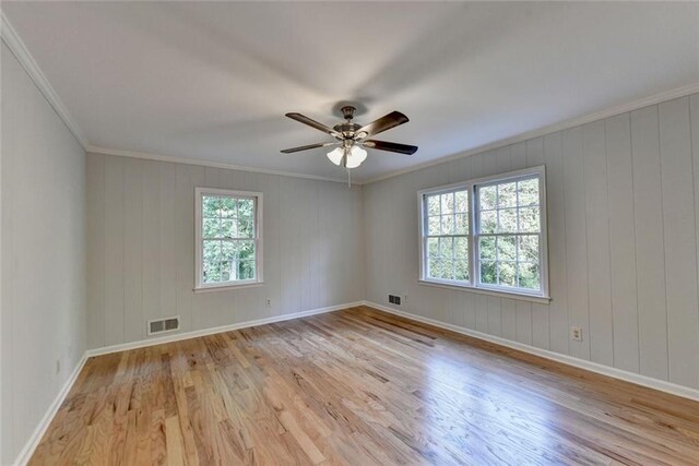 empty room with light wood-type flooring, visible vents, and crown molding