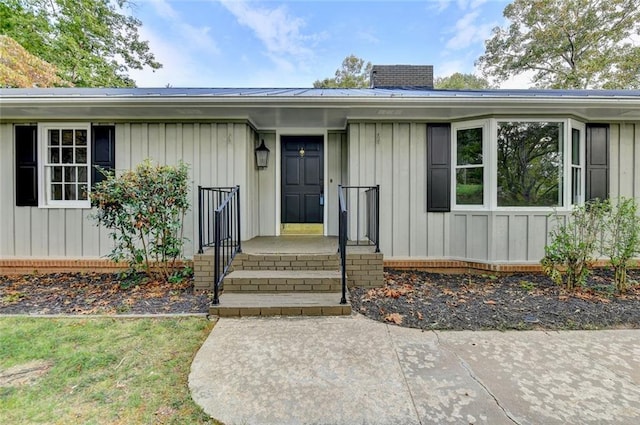 property entrance featuring board and batten siding, metal roof, and a chimney