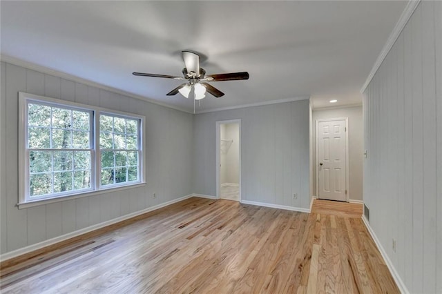 empty room featuring light wood finished floors, visible vents, ornamental molding, a ceiling fan, and baseboards