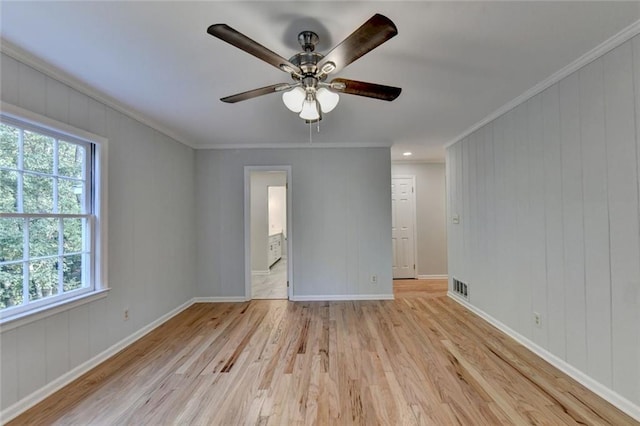 spare room featuring a ceiling fan, baseboards, visible vents, light wood finished floors, and crown molding