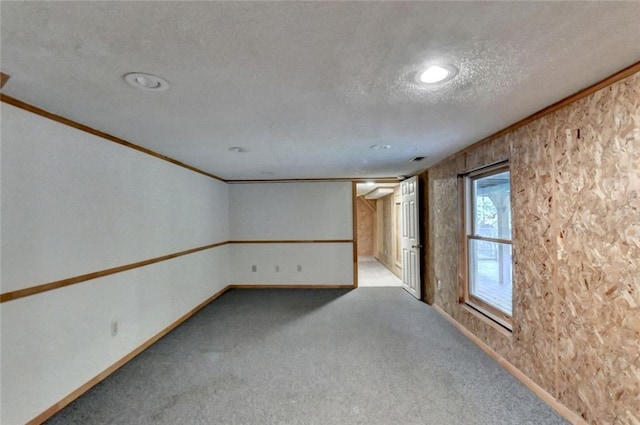 carpeted spare room featuring crown molding, a textured ceiling, and baseboards