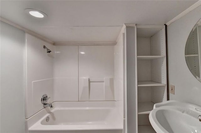 full bath featuring ornamental molding, a sink, and bathing tub / shower combination