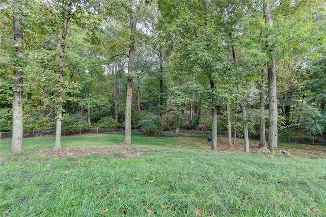 view of yard featuring a wooded view and fence