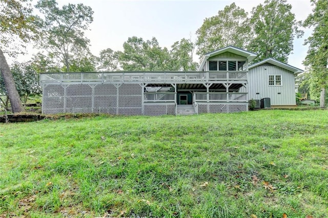 rear view of property featuring board and batten siding, a lawn, and a wooden deck