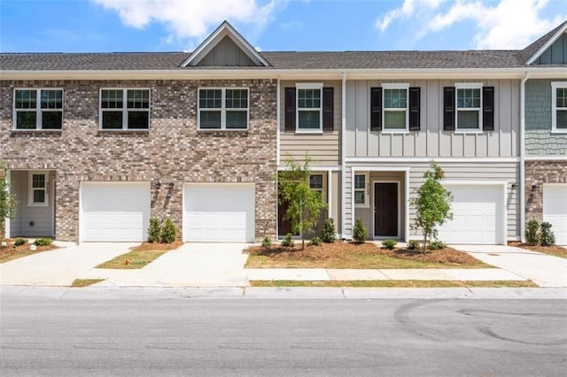 townhome / multi-family property featuring board and batten siding, brick siding, driveway, and a garage