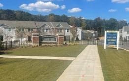 view of property's community featuring a residential view, concrete driveway, a yard, and fence