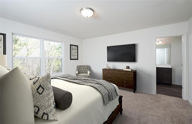 carpeted bedroom featuring connected bathroom and baseboards