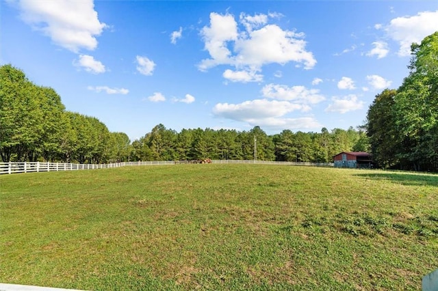 view of yard with a forest view, fence, and a rural view