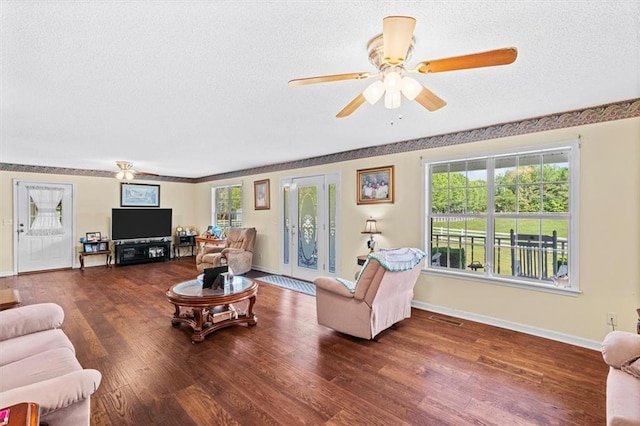 living area with a textured ceiling, ceiling fan, wood finished floors, visible vents, and baseboards