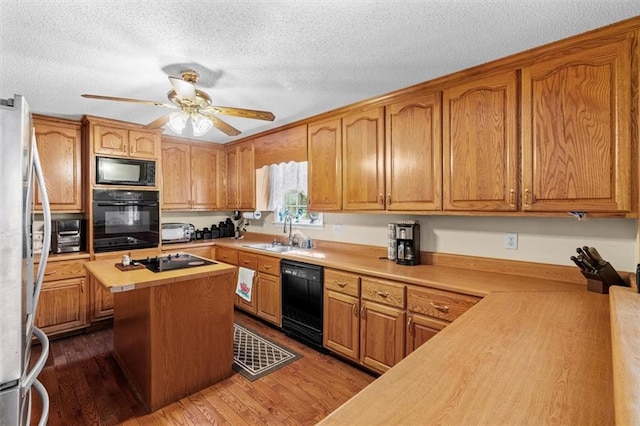 kitchen featuring ceiling fan, dark wood-type flooring, light countertops, black appliances, and a sink