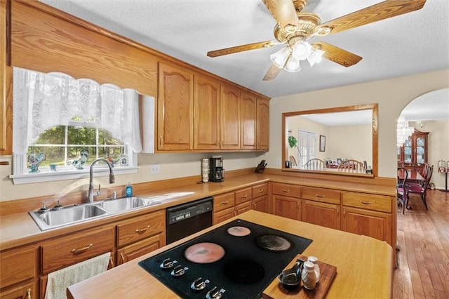 kitchen featuring black appliances, arched walkways, light countertops, and a sink