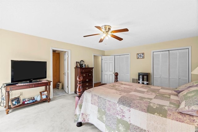 carpeted bedroom with multiple closets and a ceiling fan