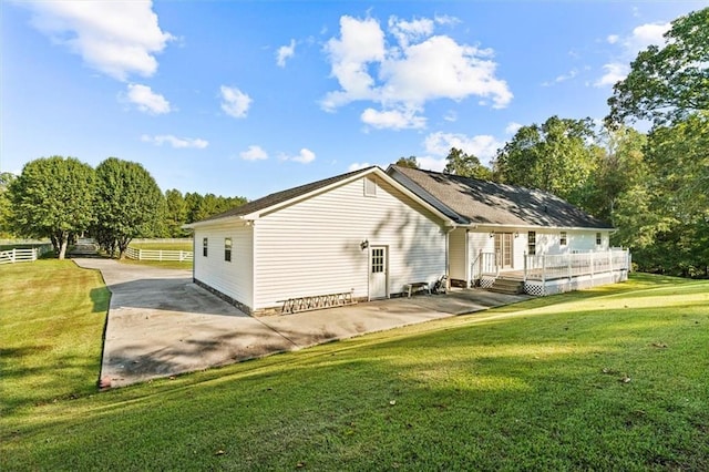 rear view of house featuring a patio area, fence, a deck, and a lawn