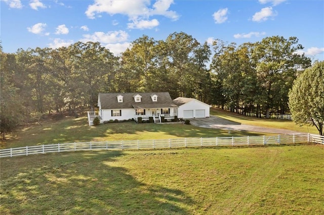 exterior space with a lawn, an attached garage, fence, a rural view, and driveway