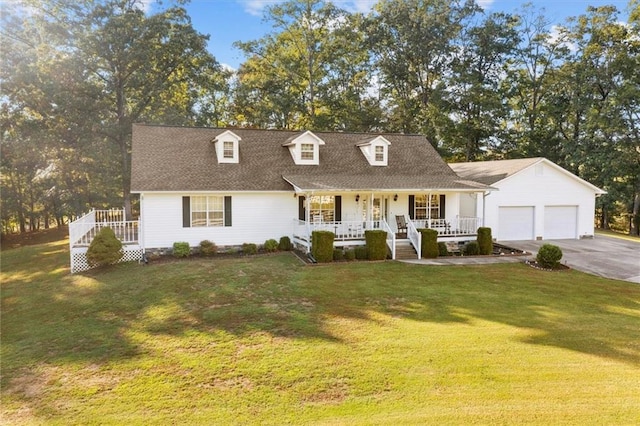 new england style home with covered porch, driveway, a front yard, and an attached garage