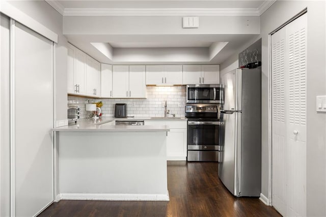 kitchen with sink, dark wood-type flooring, stainless steel appliances, ornamental molding, and white cabinets