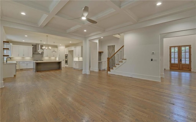 unfurnished living room featuring coffered ceiling, french doors, ceiling fan, beamed ceiling, and light hardwood / wood-style floors