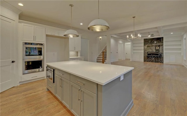 kitchen featuring a center island, hanging light fixtures, appliances with stainless steel finishes, and light hardwood / wood-style flooring