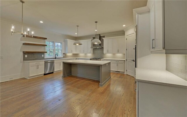 kitchen with white cabinets, wall chimney exhaust hood, light wood-type flooring, and appliances with stainless steel finishes