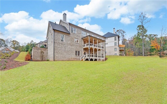 rear view of property featuring a lawn and a balcony