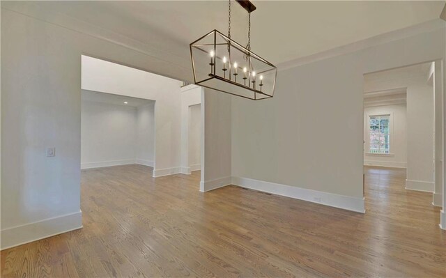 unfurnished dining area with hardwood / wood-style floors and a notable chandelier