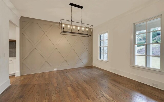 unfurnished dining area featuring dark wood-type flooring and an inviting chandelier