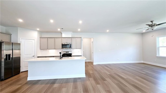 621 Pineberry Ct, Grayson, GA 30017 - kitchen with stainless steel appliances, gray cabinets, an island with sink, light wood finished floors, and baseboards
