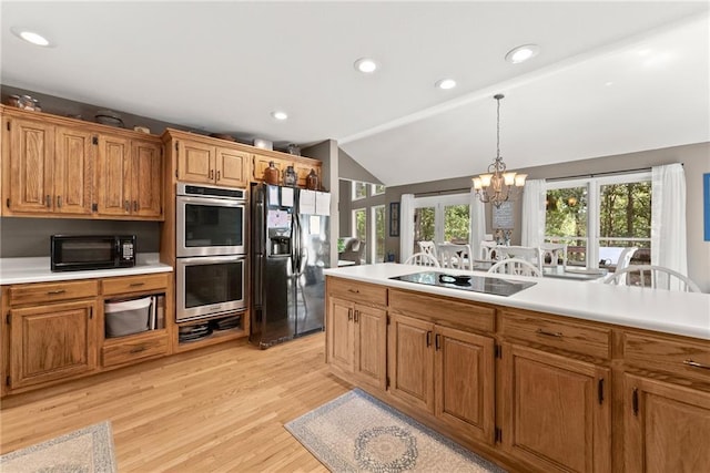 kitchen with lofted ceiling, a chandelier, light hardwood / wood-style flooring, pendant lighting, and black appliances