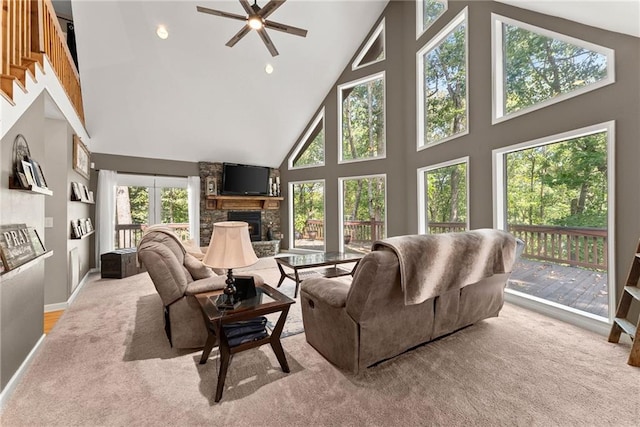 carpeted living room featuring ceiling fan, a stone fireplace, and high vaulted ceiling