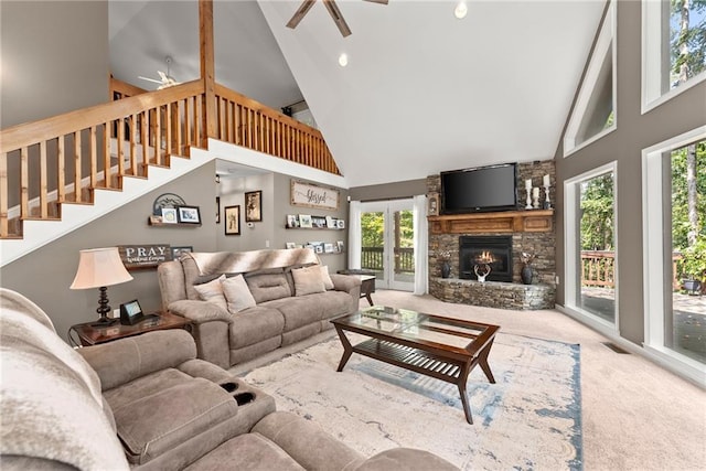 carpeted living room featuring ceiling fan, a stone fireplace, and high vaulted ceiling