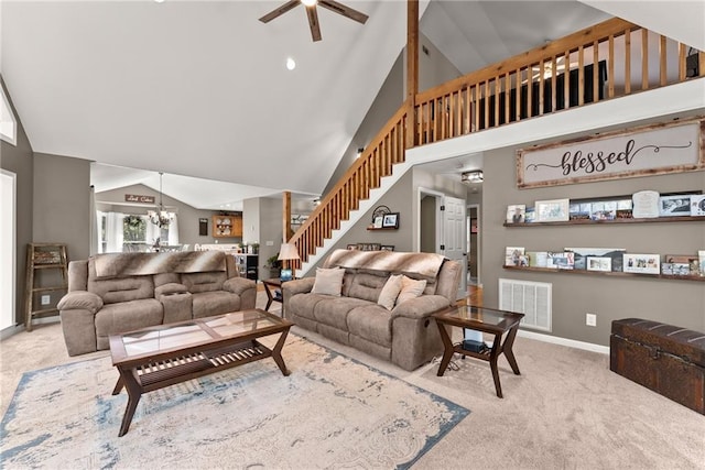 carpeted living room featuring ceiling fan with notable chandelier and high vaulted ceiling