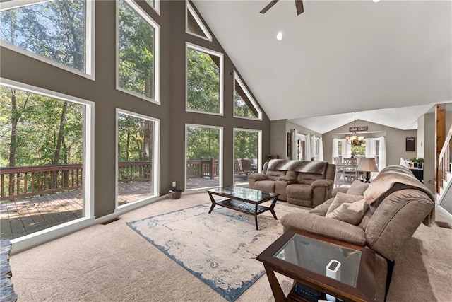 living room with ceiling fan with notable chandelier, high vaulted ceiling, and carpet