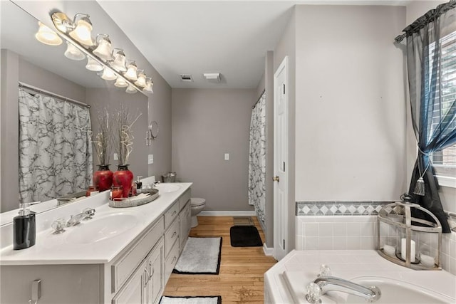 bathroom featuring vanity, a relaxing tiled tub, wood-type flooring, and a healthy amount of sunlight