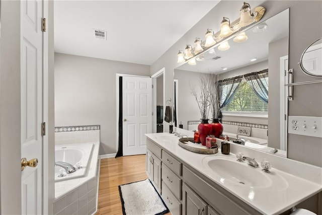 bathroom featuring hardwood / wood-style flooring, vanity, and tiled tub