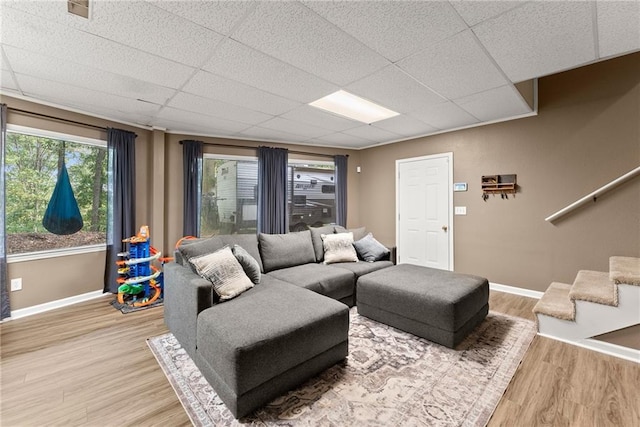 living room featuring wood-type flooring and a drop ceiling