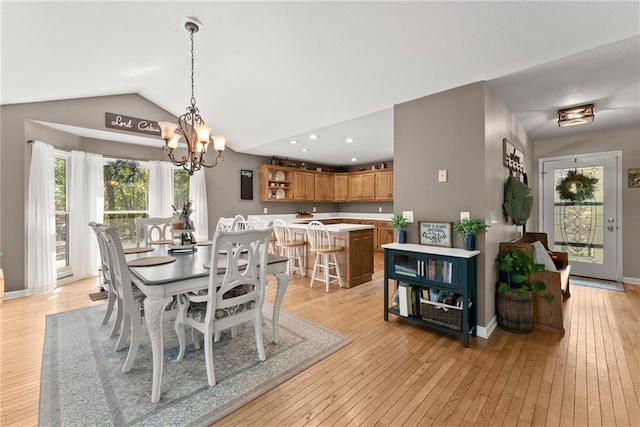 dining room featuring lofted ceiling, a chandelier, and light wood-type flooring