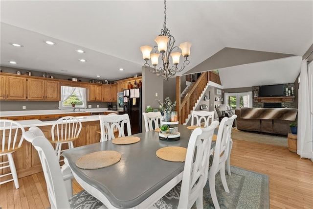 dining room with lofted ceiling, a chandelier, a fireplace, and light hardwood / wood-style flooring