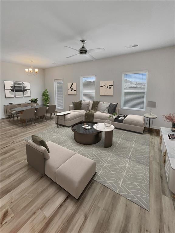 living room featuring hardwood / wood-style floors, ceiling fan with notable chandelier, and plenty of natural light