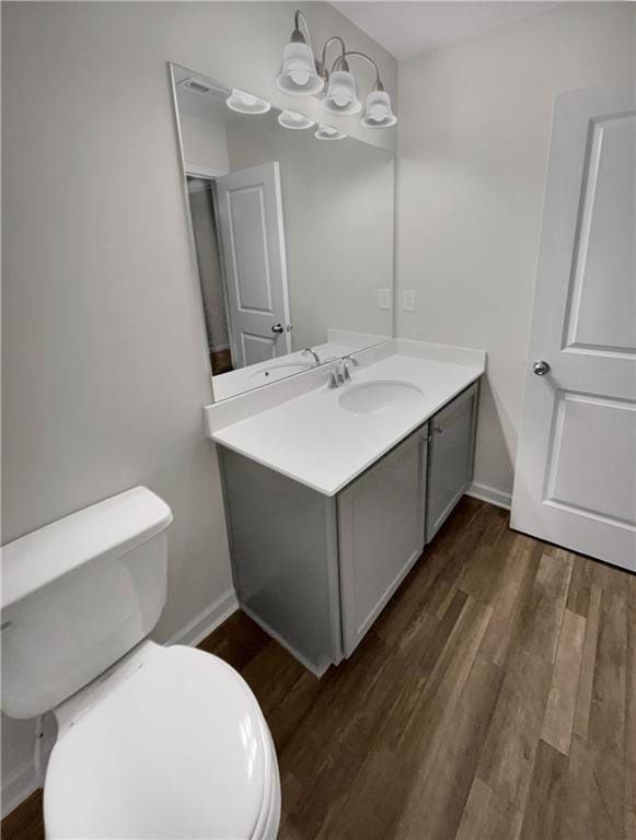 bathroom with wood-type flooring, vanity, and toilet