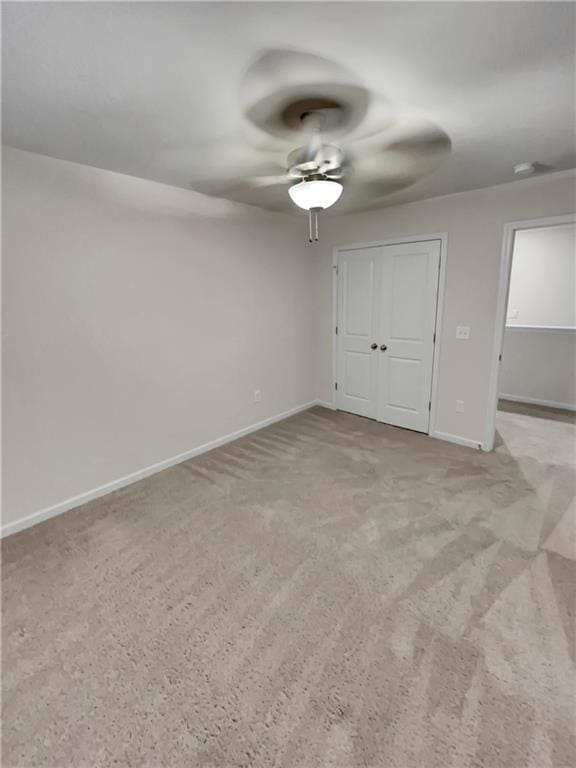 unfurnished bedroom featuring ceiling fan, light carpet, and a closet