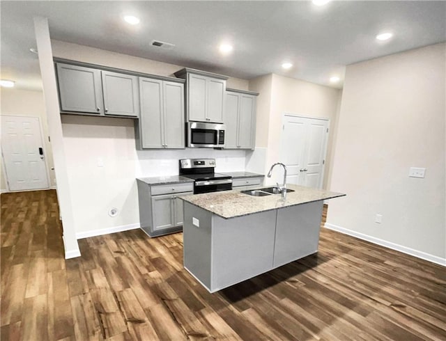 kitchen with stainless steel appliances, gray cabinets, a center island with sink, and sink