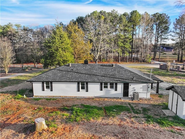 rear view of property featuring roof with shingles and central AC