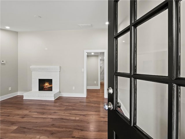 interior space with visible vents, baseboards, dark wood finished floors, a brick fireplace, and recessed lighting