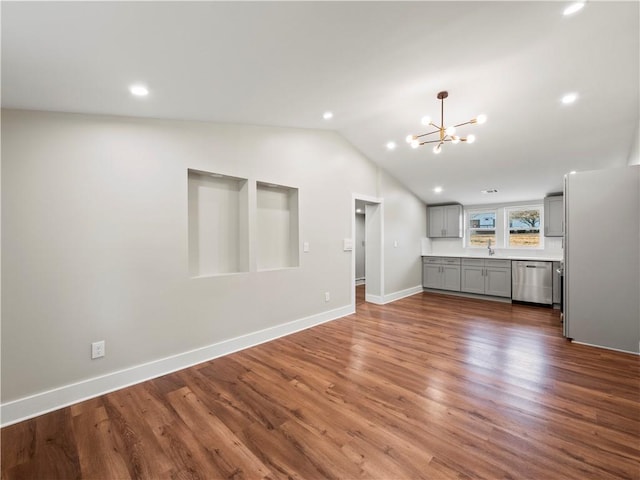 kitchen with lofted ceiling, appliances with stainless steel finishes, gray cabinets, light countertops, and a chandelier