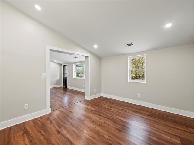 spare room featuring baseboards, visible vents, dark wood finished floors, vaulted ceiling, and recessed lighting