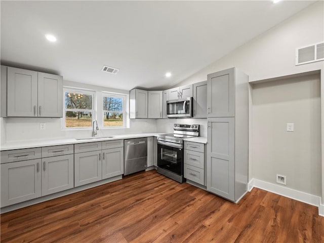 kitchen featuring vaulted ceiling, stainless steel appliances, gray cabinetry, light countertops, and a sink