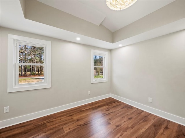 empty room featuring lofted ceiling, recessed lighting, baseboards, and wood finished floors