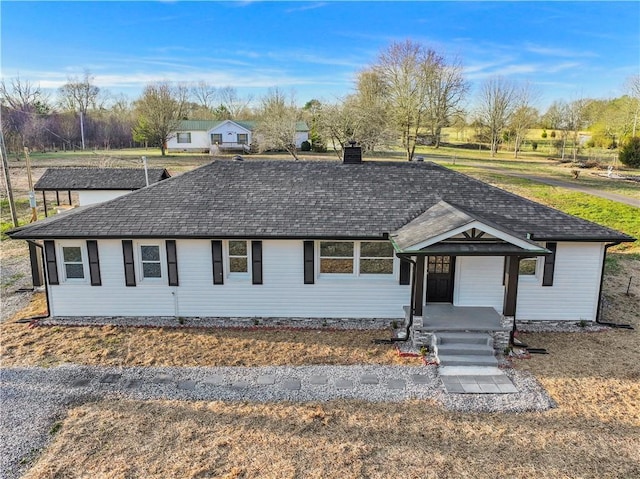 ranch-style house featuring covered porch, a chimney, and roof with shingles