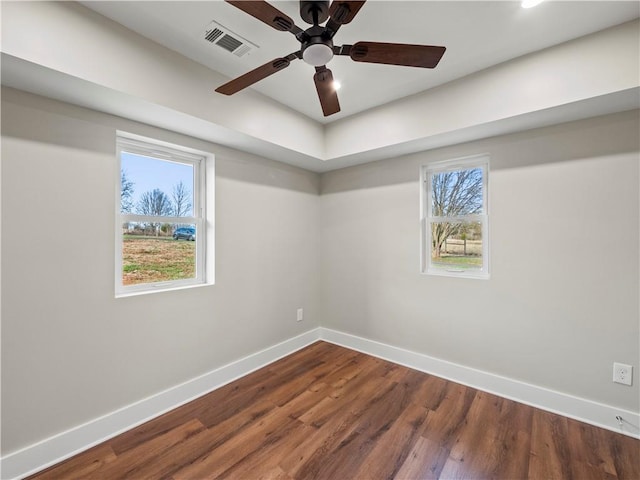 spare room with a ceiling fan, wood finished floors, visible vents, and baseboards