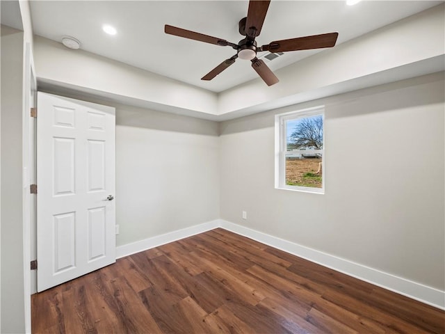 spare room featuring dark wood-style floors, ceiling fan, and baseboards